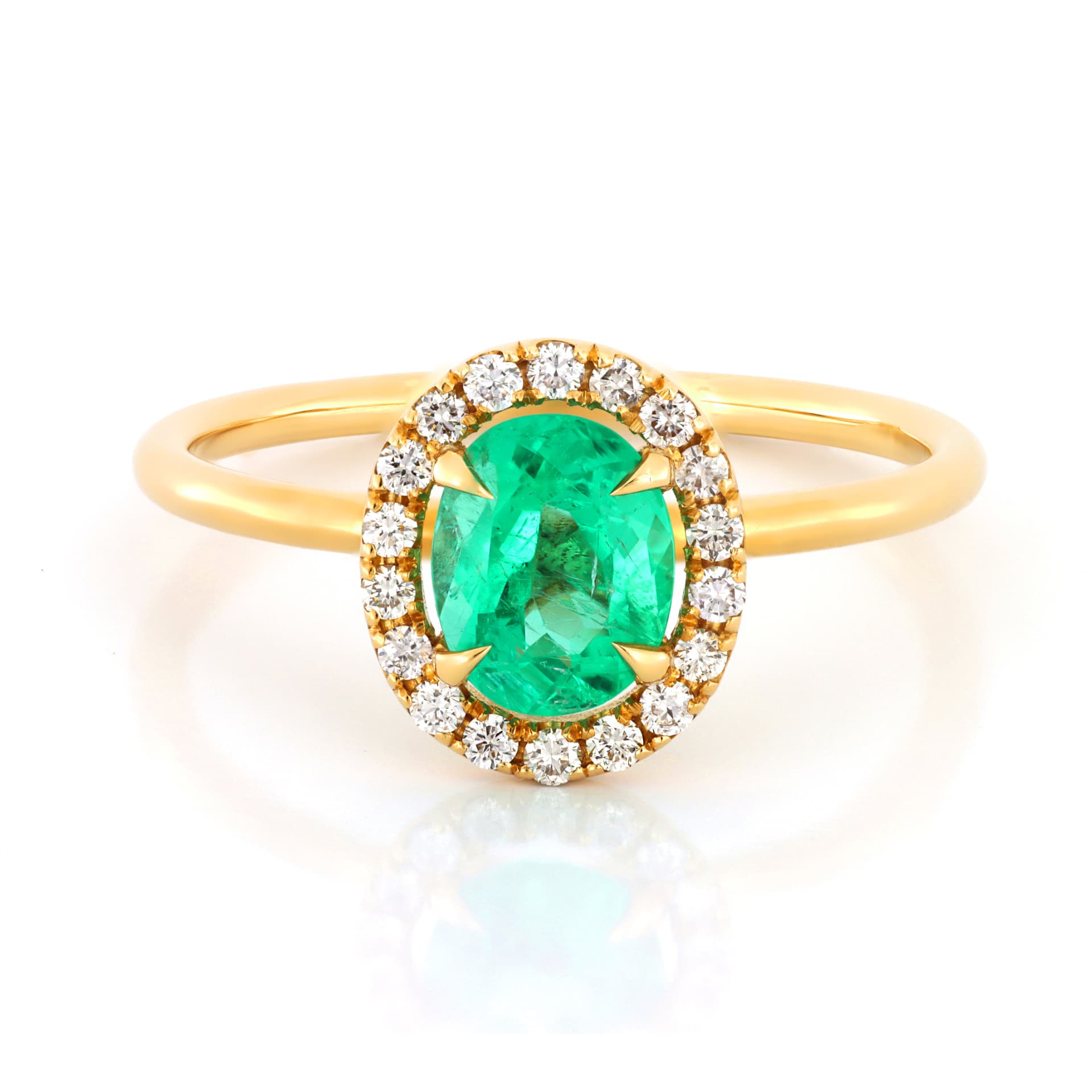 Emerald and diamond ring photographed on a rich green surface in editorial style